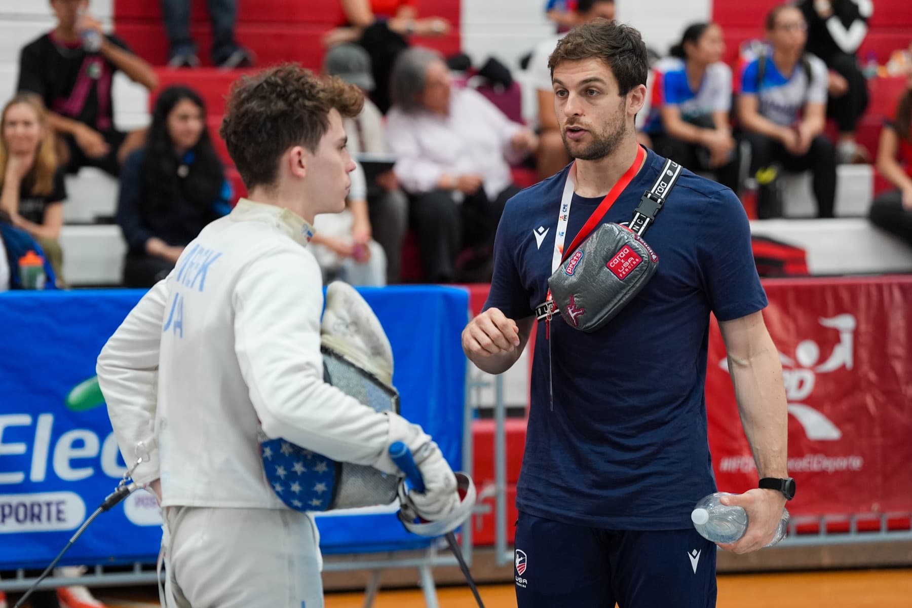 Ari coaching a young USA fencer between bouts at a competition